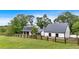 Quaint farmhouse featuring white siding, black roof, and a wooden fence, nestled among mature trees and green grass at 85 Carroll Slough Rd, Kingston, GA 30145