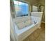 A large tub with tiled surround is located near a frosted window in the bathroom at 2520 Legend Mill Run, Dacula, GA 30019