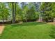 Large, green backyard surrounded by trees and a wooden fence, perfect for outdoor activities at 3700 Sexton Woods Dr, Chamblee, GA 30341