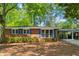 Charming one-story brick home with blue shutters and a cozy carport surrounded by mature trees at 3700 Sexton Woods Dr, Chamblee, GA 30341