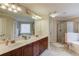 Bathroom features double sinks, cherry cabinets, a large mirror, a glass-enclosed shower, and a soaking tub at 1633 Park Hollow Ln, Lawrenceville, GA 30043