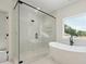 Modern bathroom featuring a glass enclosed shower and a separate soaking tub next to a bright window at 3930 Clifton Hill Court #15, Cumming, GA 30040