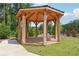 Wooden gazebo with wood flooring sits on green grass with trees in the background at 3930 Clifton Hill Court #15, Cumming, GA 30040