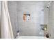 Shower featuring gray tiles, a shower head, and recessed shelving for storage at 493 James Street Sw, Lilburn, GA 30047