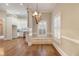 Dining room features hardwood floors, a chandelier, and wainscoting, with a view into the kitchen at 1418 Brighton Pl, Loganville, GA 30052
