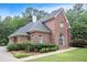 Exterior view of brick home showcasing manicured landscaping, lush lawn and mature trees at 1418 Brighton Pl, Loganville, GA 30052