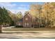 Charming brick home featuring a well-manicured lawn and mature trees under a bright blue sky at 1418 Brighton Pl, Loganville, GA 30052
