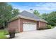 Side view of brick home with a two-car garage, new roof, and mature landscaping at 1418 Brighton Pl, Loganville, GA 30052