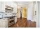 Charming kitchen features white cabinets, stainless appliances, hardwood floors and adjacent rooms at 1418 Brighton Pl, Loganville, GA 30052
