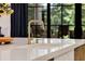 Close up of kitchen sink with white countertops and a gold faucet with black trimmed windows in background at 542 Orme Ne Cir, Atlanta, GA 30306