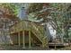 View of a wooden deck with staircase with a chimney in the background partially obscured by trees at 455 Tyson Cir, Roswell, GA 30076