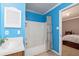 Bright, blue bathroom featuring a shower-tub combo, single sink vanity, and view into the bedroom at 4960 Old Yorkville Rd, Dallas, GA 30157