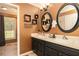 Bathroom with double vanity, decorative oval mirrors, warm lighting and adjoining room with window and tile floor at 4960 Old Yorkville Rd, Dallas, GA 30157