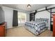 Comfortable bedroom featuring a plaid bedspread, bright window, and dark wood shelves and dresser at 4960 Old Yorkville Rd, Dallas, GA 30157