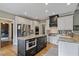 Spacious kitchen with custom cabinetry, granite countertops, an island with an oven, and stainless appliances at 295 Sagamore Nw Cv, Sugar Hill, GA 30518