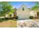 Charming yellow two-story home featuring an attached two car garage and mature landscaping at 545 Goldfinch Way, Stockbridge, GA 30281