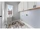 Functional laundry room includes a utility sink, upper cabinets, and stylish marble-look flooring at 6091 Wayfarer Dr, Villa Rica, GA 30180