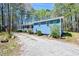 Angled view of the blue home with long porch and gravel driveway, nestled among trees at 5955 Kemp Dr, Acworth, GA 30102