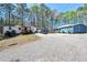 Exterior shot of two homes with mature trees and gravel driveway on a sunny day at 5955 Kemp Dr, Acworth, GA 30102