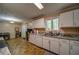Long kitchen with granite countertops, white cabinetry, and appliances, leading to the dining area at 5955 Kemp Dr, Acworth, GA 30102