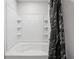 Clean bathtub and shower with tiled walls, shelving, and a modern black patterned shower curtain at 89 Cowpen Ct, Covington, GA 30014