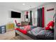 Bedroom features neutral carpeting, a mounted television, and a queen bed with black and red linens at 89 Cowpen Ct, Covington, GA 30014