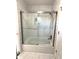 Bright bathroom featuring a tub with glass shower doors and modern marble-style tiling at 9450 Knollcrest Blvd, Alpharetta, GA 30022