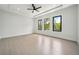 Bright bedroom with tray ceiling, ceiling fan, and three windows overlooking trees at 155 Westbrook St, Buford, GA 30518