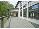 Rear view of an outdoor deck with sleek railings, overlooking a tree-lined yard with a white brick exterior at 155 Westbrook St, Buford, GA 30518