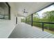 Covered outdoor deck with a fan, white brick, and sleek, dark railings overlooking the tree-lined yard at 155 Westbrook St, Buford, GA 30518