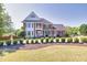 Stately brick home featuring a manicured lawn, mature landscaping, and classic architectural details under a clear blue sky at 1135 Azalea Cir, Conyers, GA 30013