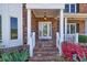 Charming brick home featuring a covered front porch with a decorative glass front door and manicured landscaping at 1135 Azalea Cir, Conyers, GA 30013