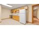 Compact kitchen with wood cabinets, white appliances, and tile flooring with adjacent hallway at 1135 Azalea Cir, Conyers, GA 30013