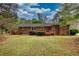 Expansive backyard featuring mature trees, lush lawn, and a charming brick home with a wooden deck at 1311 Maple Street Se, Conyers, GA 30013