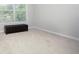 Empty bedroom with neutral carpet, window, and dark brown ottoman bench at 3080 W Jackson Way, Austell, GA 30106