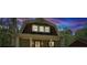 Charming home featuring a unique gambrel roof, covered porch with columns, and warm exterior lighting at 3125 Lakeside Dr, Cumming, GA 30041