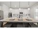 Close up kitchen island with seating, pendant lights and white cabinetry and countertop at 3265 Lions Ruby Ln, Atlanta, GA 30349