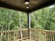 Relaxing covered back porch with wooden railing offers views of the lush greenery at 6132 Hutchins Dr, Buford, GA 30518