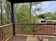 Covered back porch featuring a wooden railing with serene backyard view at 6132 Hutchins Dr, Buford, GA 30518