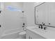 Bright bathroom featuring a tub with white tile surround and a vanity with black modern fixtures at 6132 Hutchins Dr, Buford, GA 30518