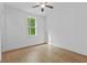 Neutral bedroom with wood floors, ceiling fan, and a bright window looking out on lush greenery at 6132 Hutchins Dr, Buford, GA 30518