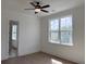 Bright bedroom featuring a ceiling fan, light hardwood floors and a large window overlooking lush greenery at 6132 Hutchins Dr, Buford, GA 30518
