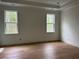 Spacious bedroom with hardwood floors, two windows, and modern tray ceiling at 6132 Hutchins Dr, Buford, GA 30518