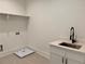 Functional laundry room with a stainless steel sink, modern faucet, and ample cabinet space at 6132 Hutchins Dr, Buford, GA 30518