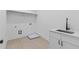 Laundry room with white cabinets, sleek black faucet and sink, hanging rack, and vinyl flooring at 6132 Hutchins Dr, Buford, GA 30518