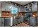 Gray kitchen with stainless steel appliances, wood countertops, wooden backsplash and a farmhouse sink at 1337 Frontier Trl, Sugar Hill, GA 30518