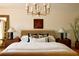 Bedroom with neutral tones featuring a large bed, chandelier, and lamps at 902 Lenox Hill Ne Ct, Atlanta, GA 30324