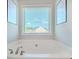 A luxurious soaking tub area with a serene view through the window, framed by modern art at 113 Cottage Walk, Cartersville, GA 30121