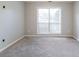 Empty bedroom featuring grey walls, light carpet, and a large window with neutral shades at 334 Royal Crescent Way, Stockbridge, GA 30281