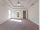 Spacious carpeted main bedroom with tray ceilings, a fan, and natural light at 334 Royal Crescent Way, Stockbridge, GA 30281